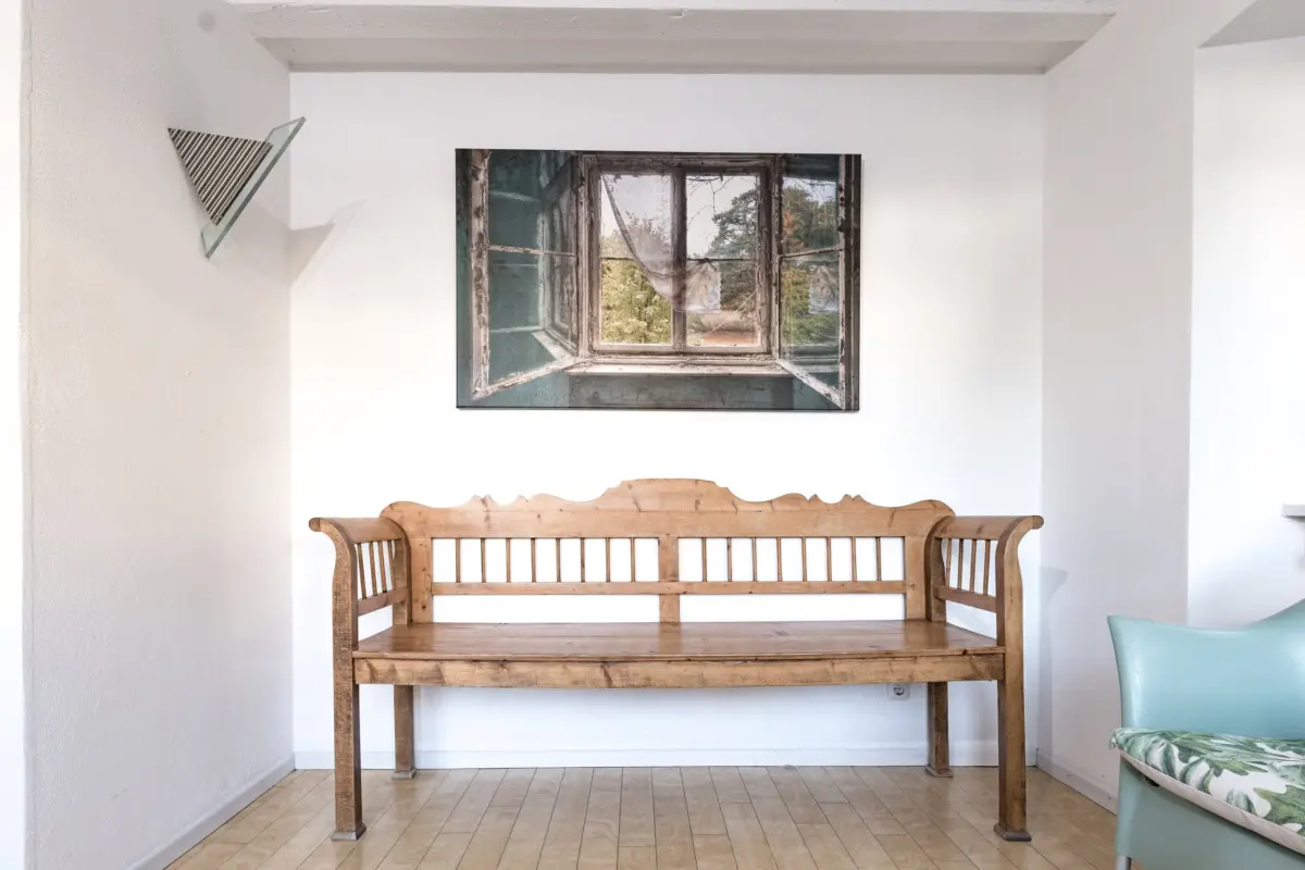 Wartebereich der Praxis mit Holzbank und Bild an der Wand